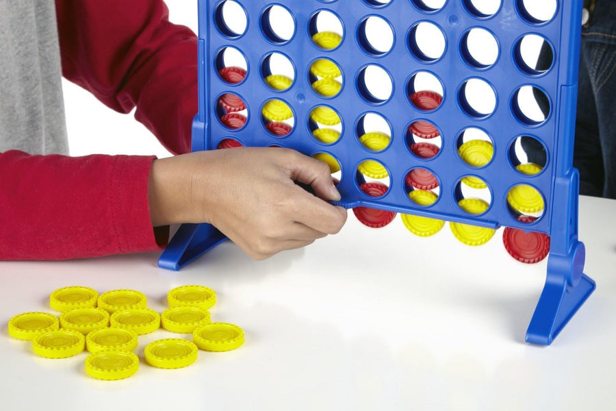 Hasbro Connect 4 board game with colorful red and yellow discs arranged in a grid on a game table.